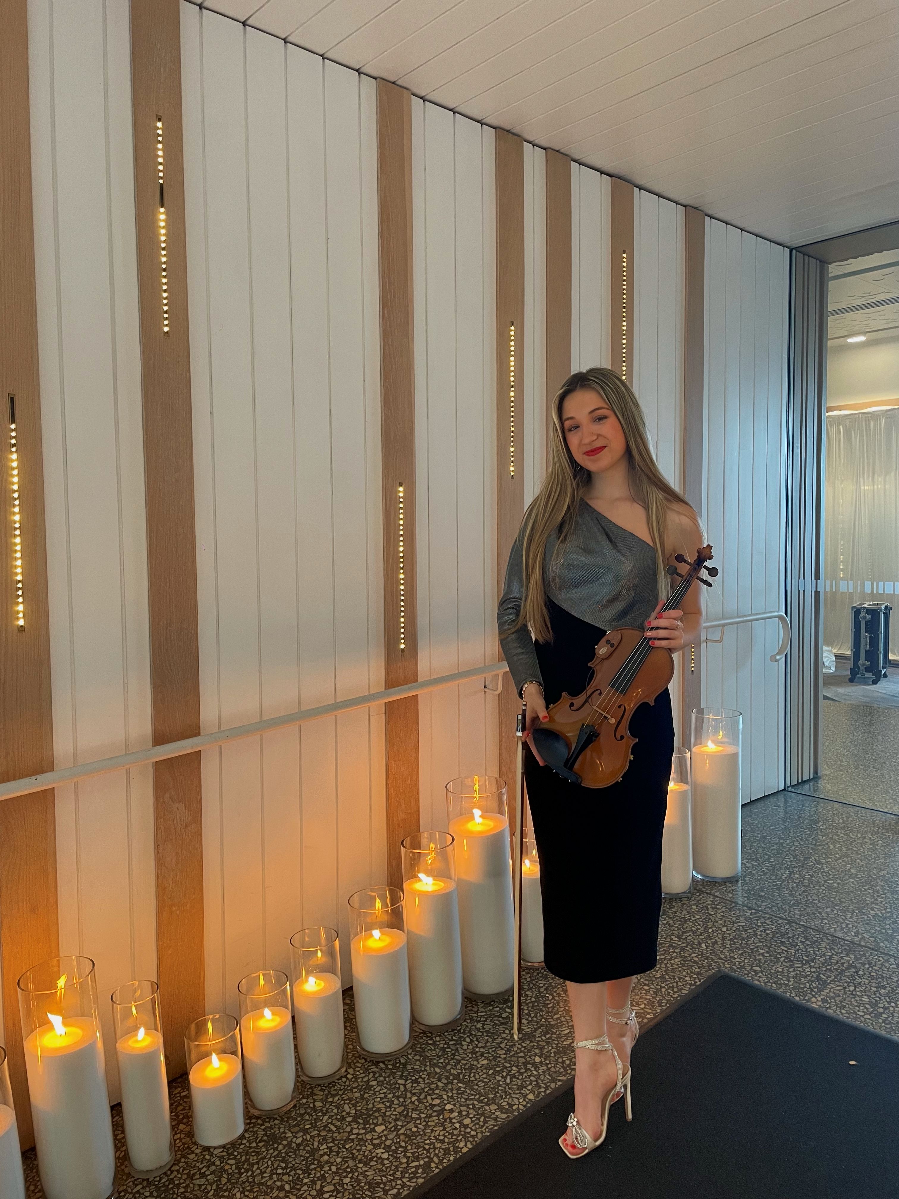 Tali in a grey and black dress holding violin
